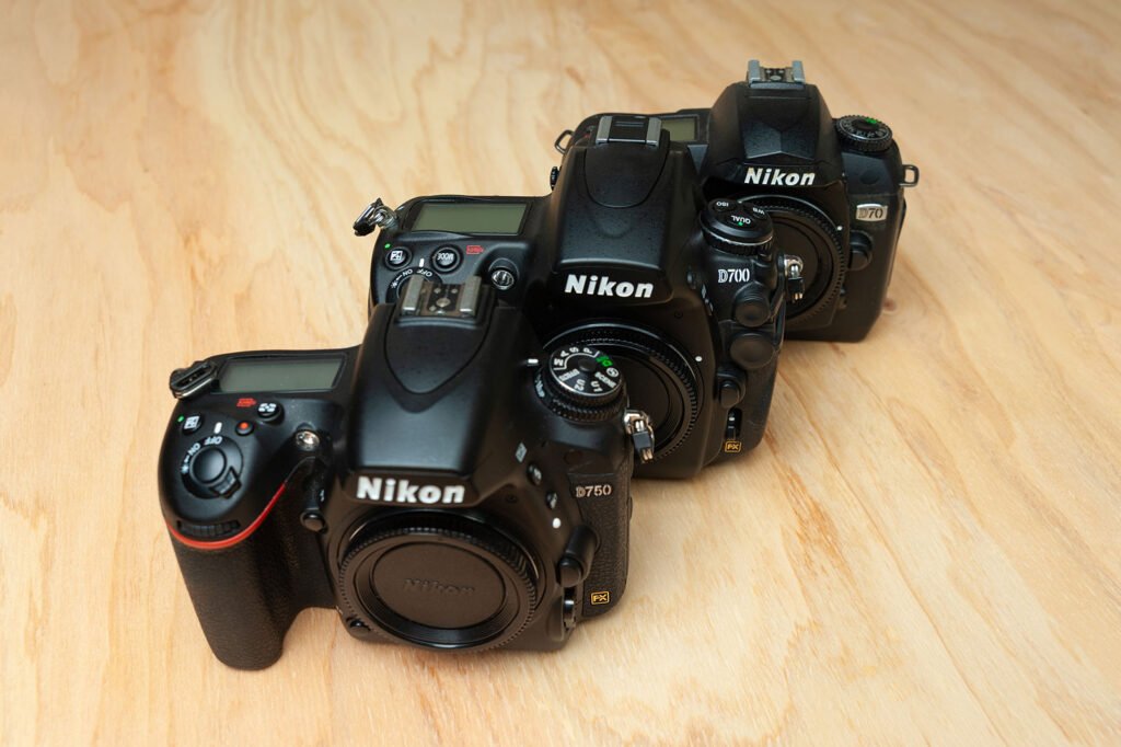 Nikon D70, D700 and D750 cameras together on wooden surface