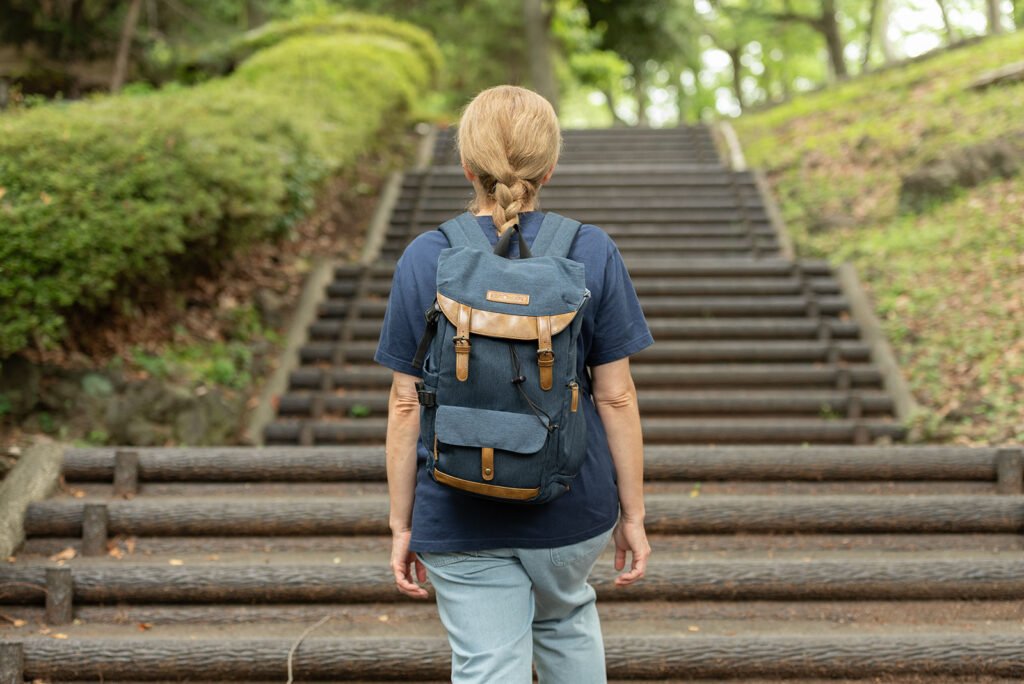 Photographer carrying a K&F Concept vintage camera backpack on a stairway in Japan